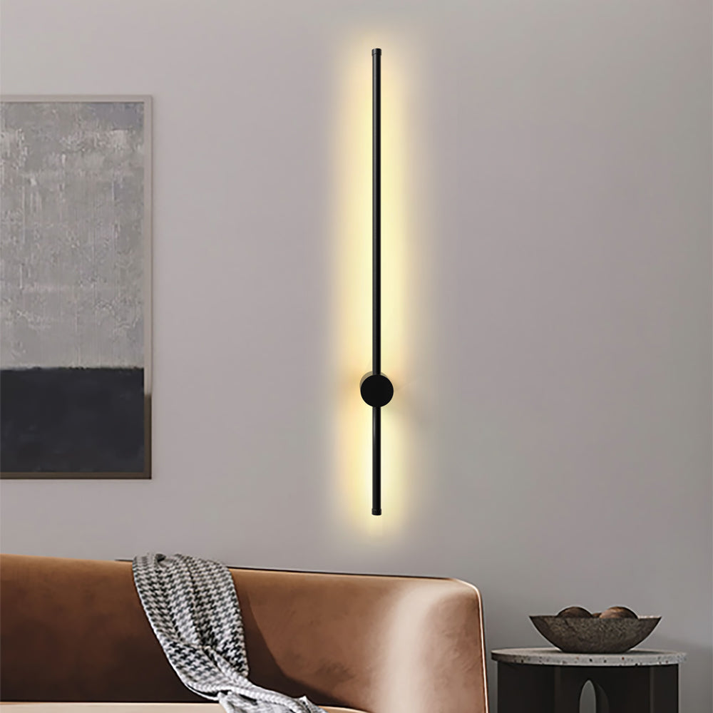 Warm ambient light radiating from a vertical rotatable linear wall fixture above a brown sofa