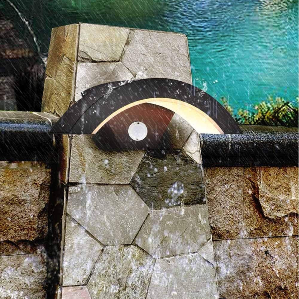 Waterproof arched garden wall light illuminating a decorative outdoor stone wall