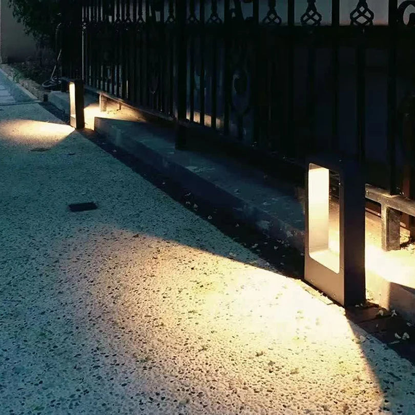 IP65 waterproof LED walkway bollard casting a warm downward glow along a path next to a fence