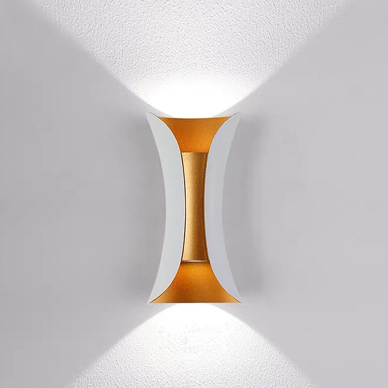 Elegant white and gold hourglass outdoor wall lamp creating a distinct light and shadow pattern