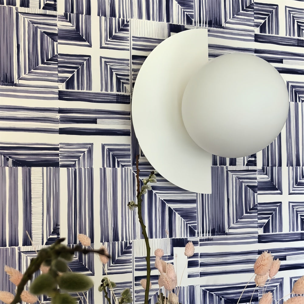 Clean white Bauhaus wall sconce styled perfectly against striking blue geometric wallpaper