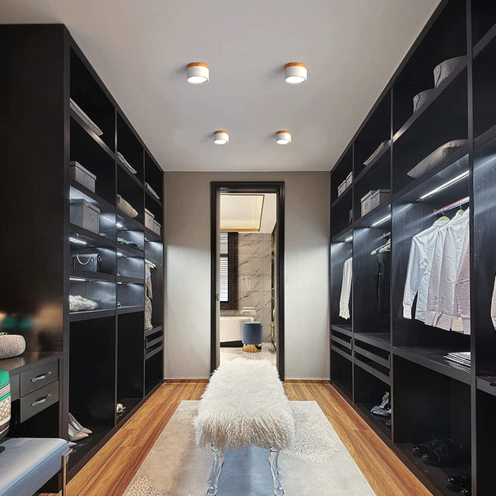Multiple white cylinder flush ceiling lights illuminating a dark modern walk-in wardrobe