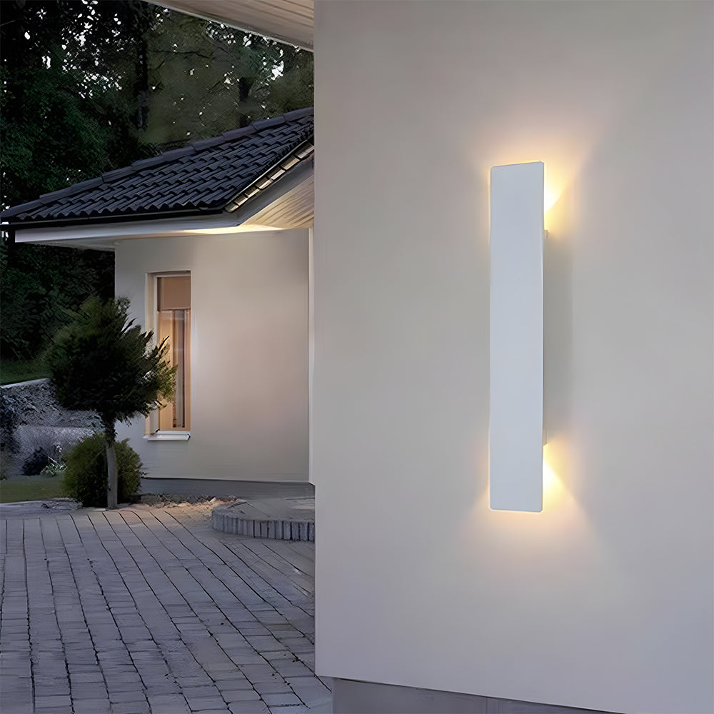 White IP65 exterior wall light illuminating the corner wall of a residential driveway