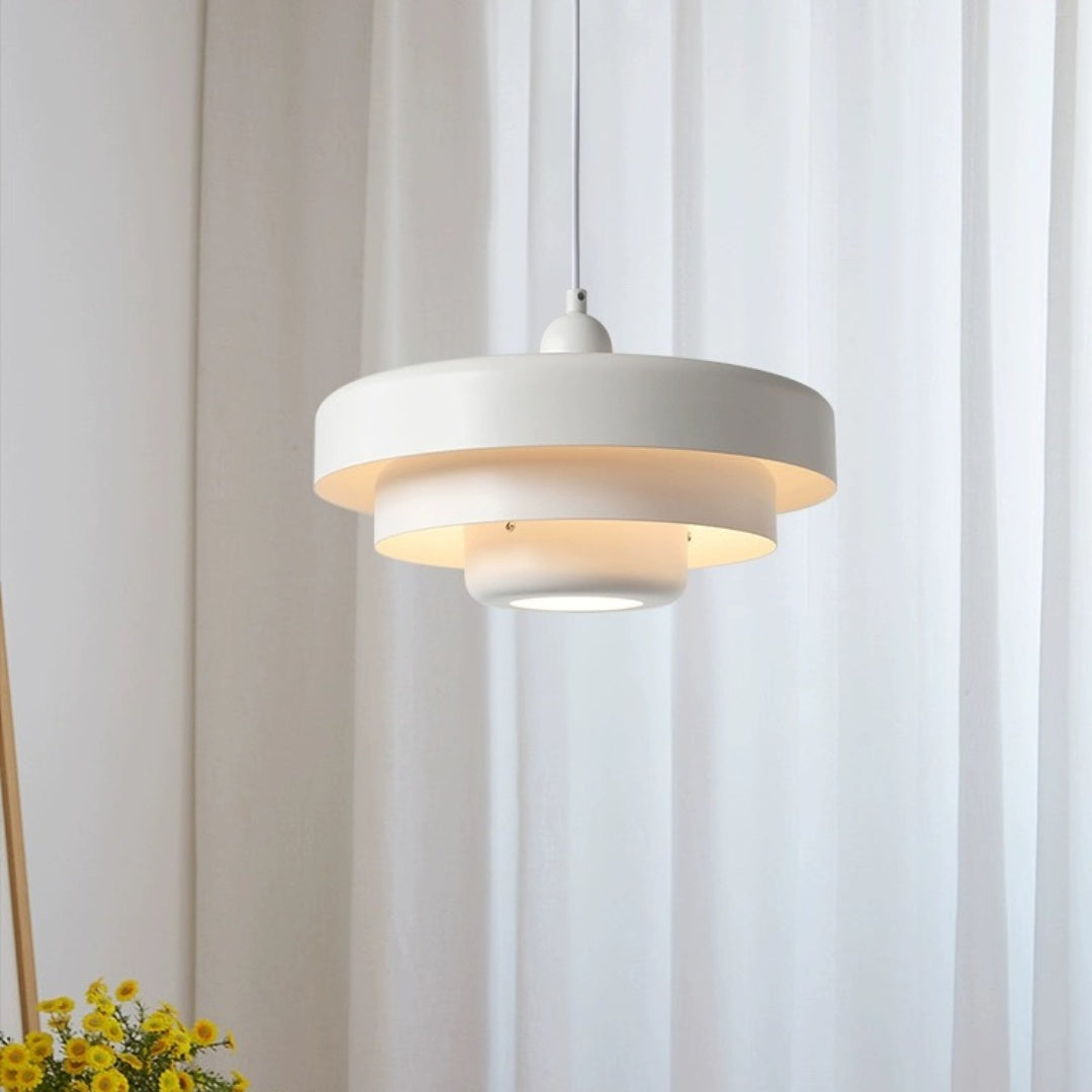 Single white layered metal pendant light suspended in a bright, minimalist reading nook