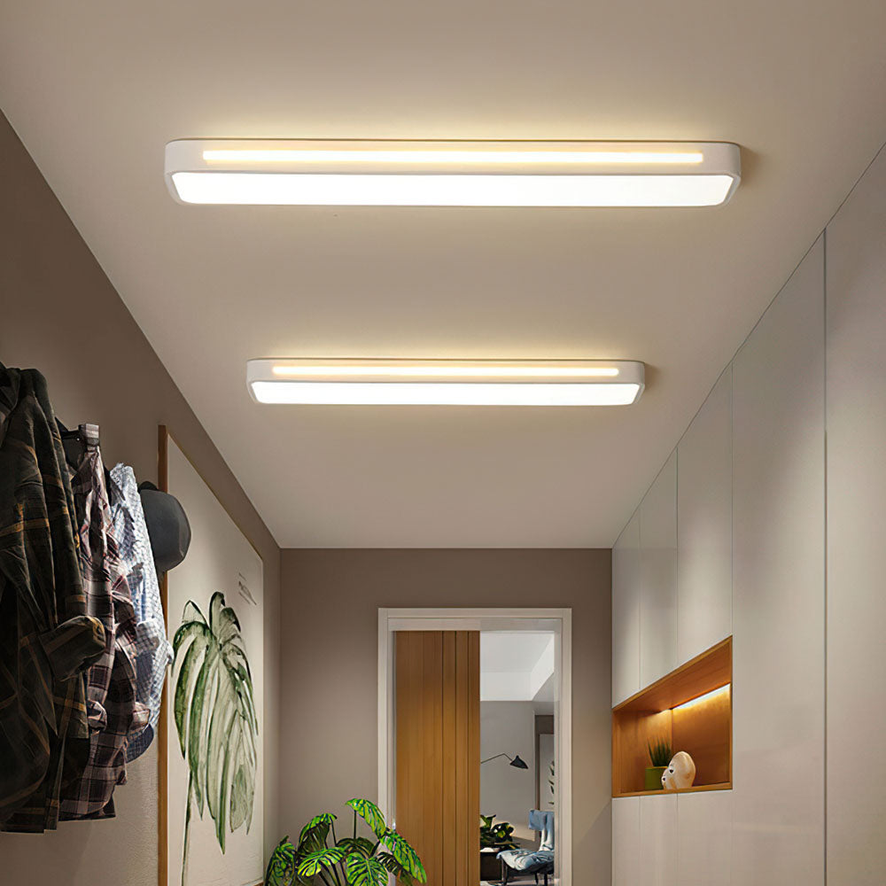 Two modern white linear flush mount ceiling lights installed in a bright minimalist hallway