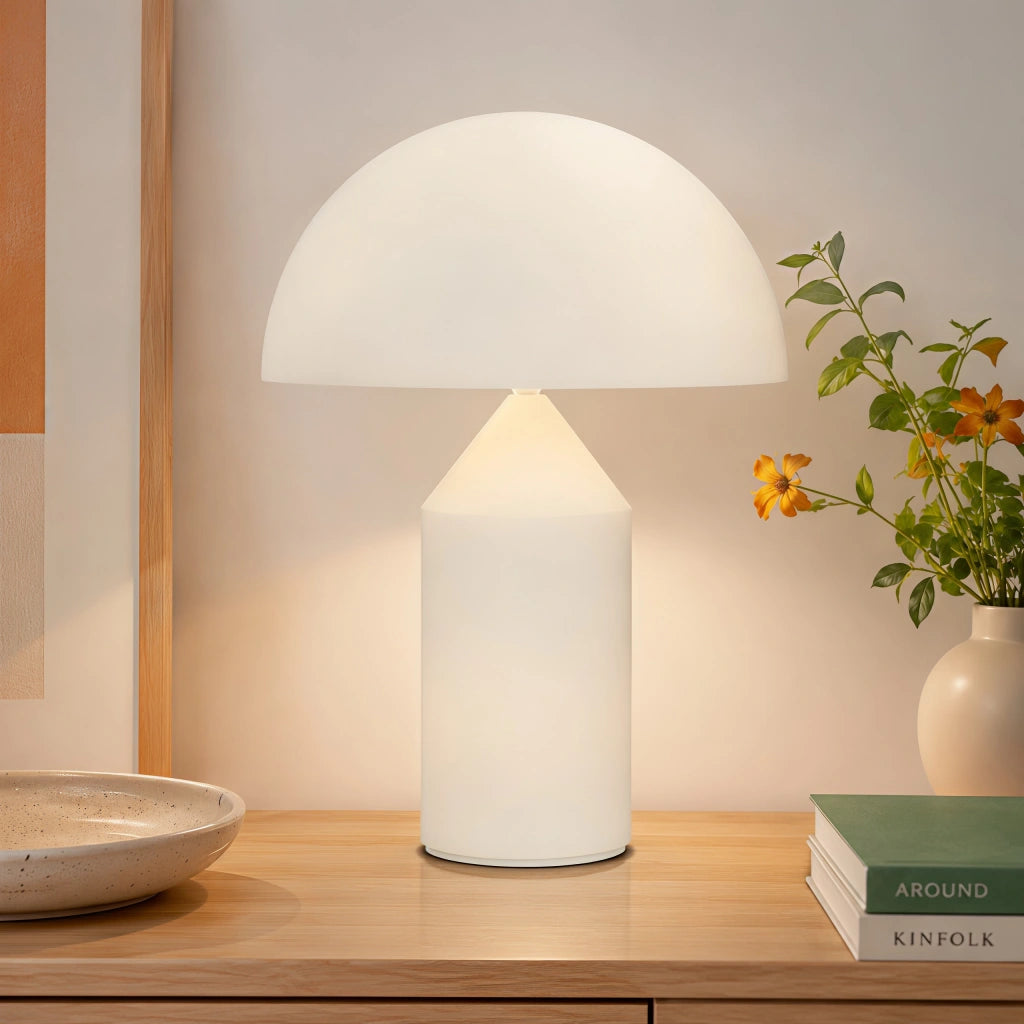 White mid-century dome lamp providing warm ambient light on a rustic wooden desk