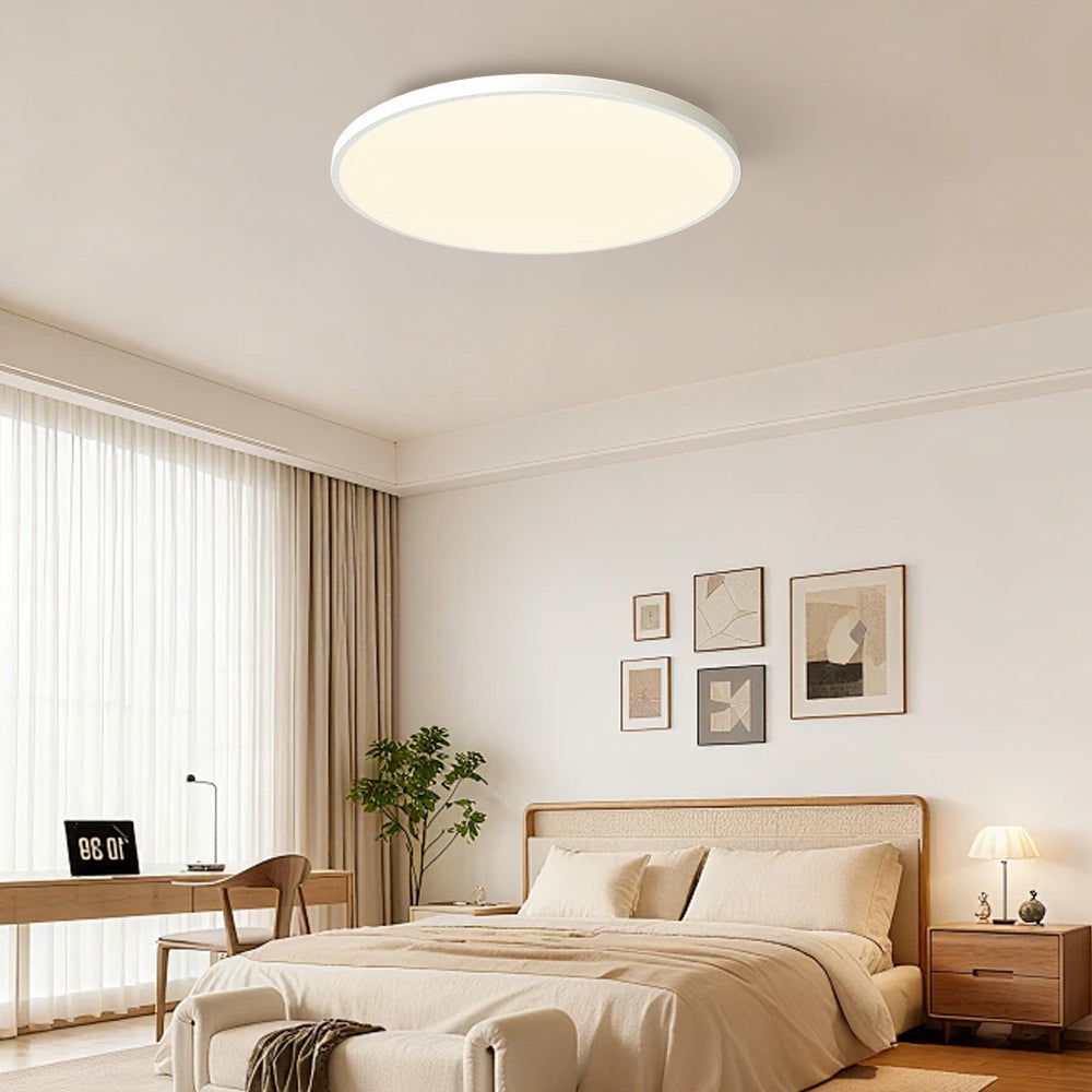 White minimalist flush mount ceiling light illuminating a bright home office and bedroom space