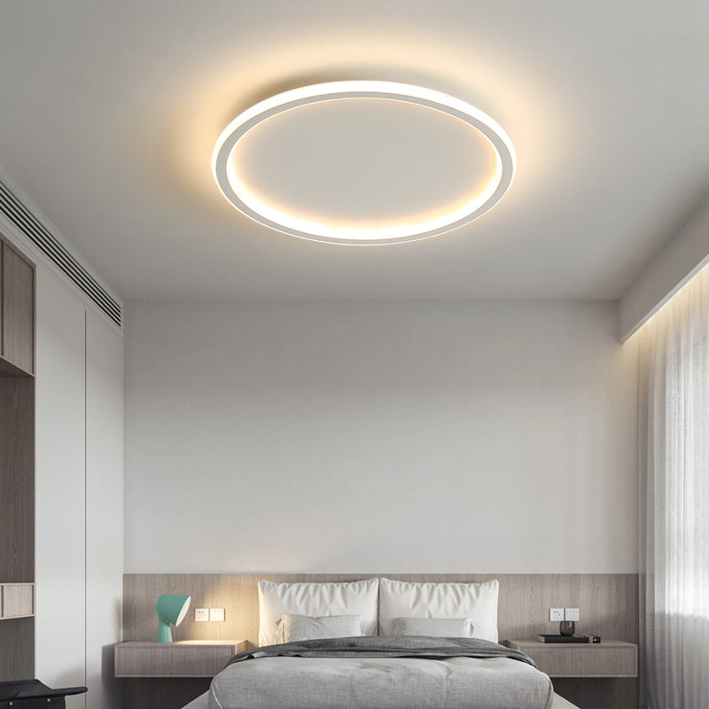 Clean white minimalist ring ceiling lamp casting a smooth, glare-free glow in a bright bedroom