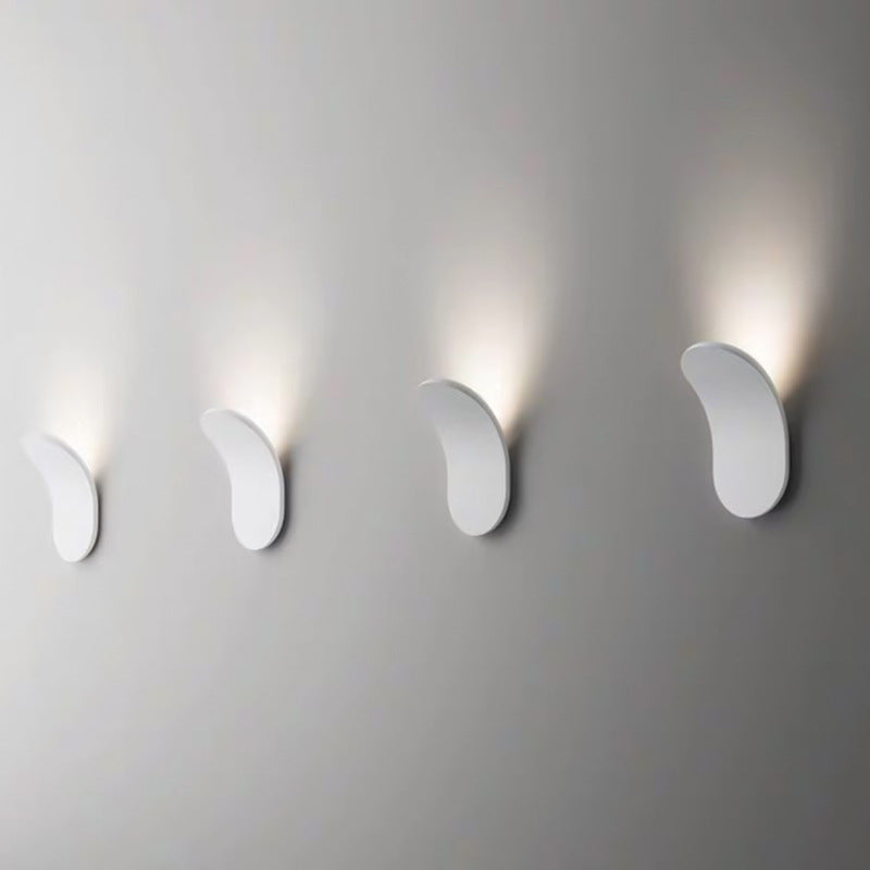 Four white minimalist wall sconces providing rhythmic indirect lighting along a corridor wall