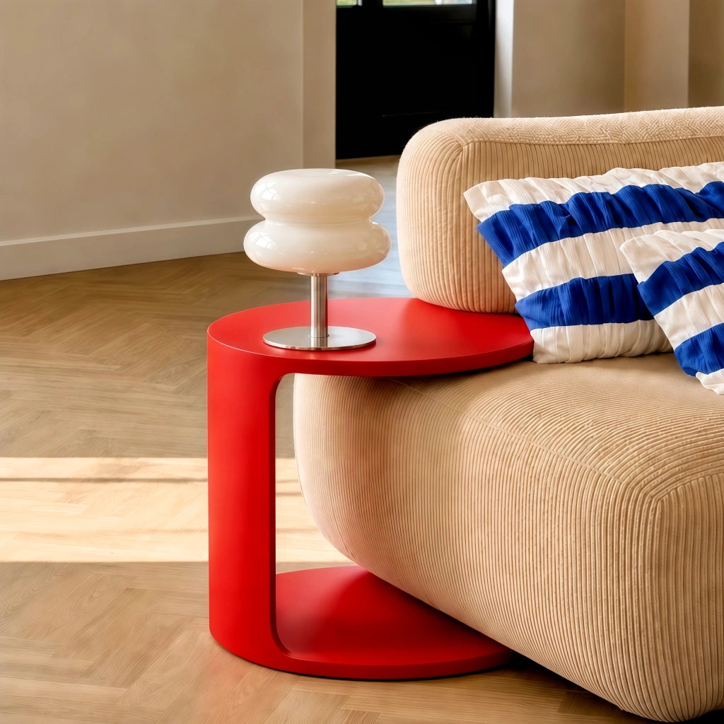 White stacked glass reading lamp styled on a modern red C-shaped side table next to a sofa