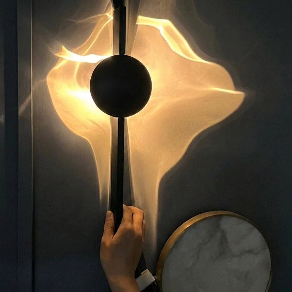 Close-up of a hand adjusting the black disc head on the Wobzi wall sconce