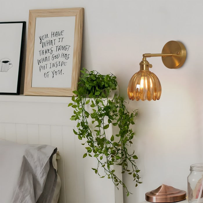 Amber xetyl lotus bedside wall sconce illuminating a nightstand with trailing indoor plants