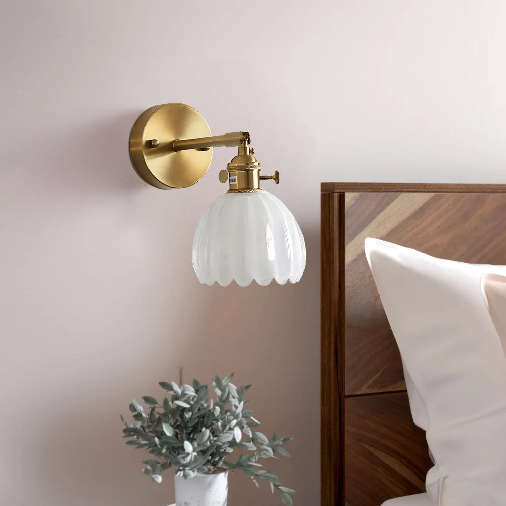 White floral glass xetyl sconce mounted above a bedside table in a cosy, neutral bedroom