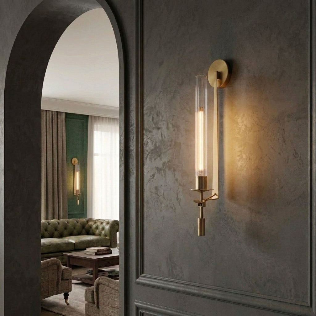 Xilpo Satin Gold wall sconce mounted on a dark textured wall with a green chesterfield sofa in the other room