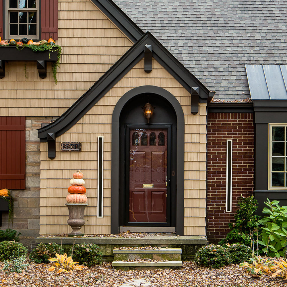 Long black xura outdoor wall lights flanking a classic wooden front door on a brick house