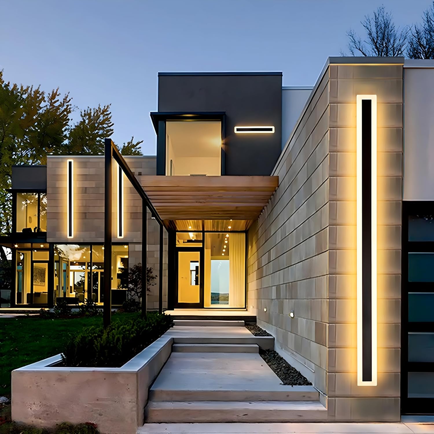 Pair of tall linear exterior xura LED wall lights illuminating the entrance of a luxury modern home at dusk