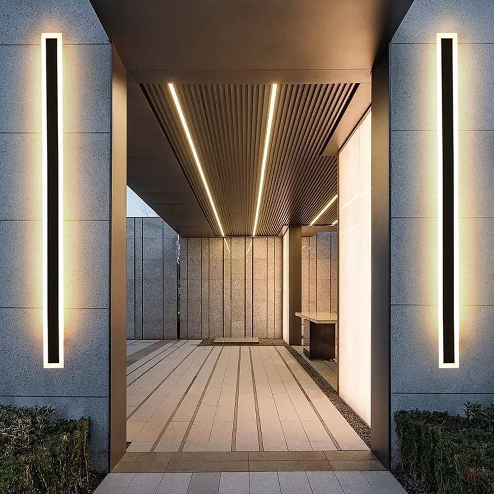 Pair of long xura linear exterior LED sconces illuminating a modern covered walkway