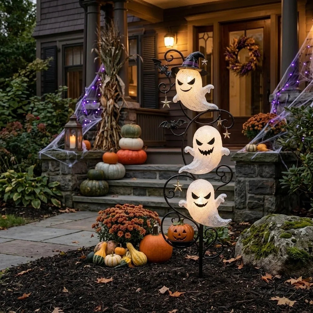 Yardmarker LED ghost garden stake glowing beside porch steps with pumpkins and cobwebs