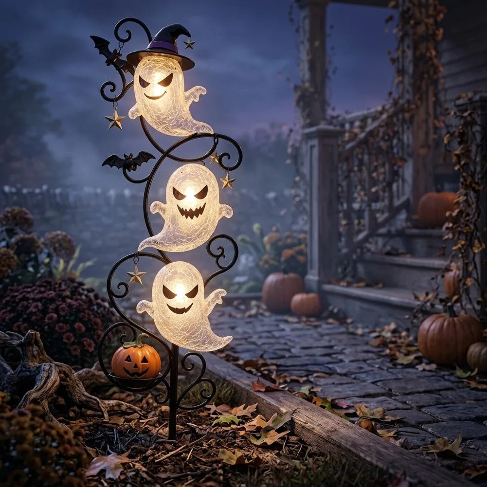 Yardmarker LED glowing ghost garden stake with witch hat and jack-o'-lantern staked beside a stone path at dusk