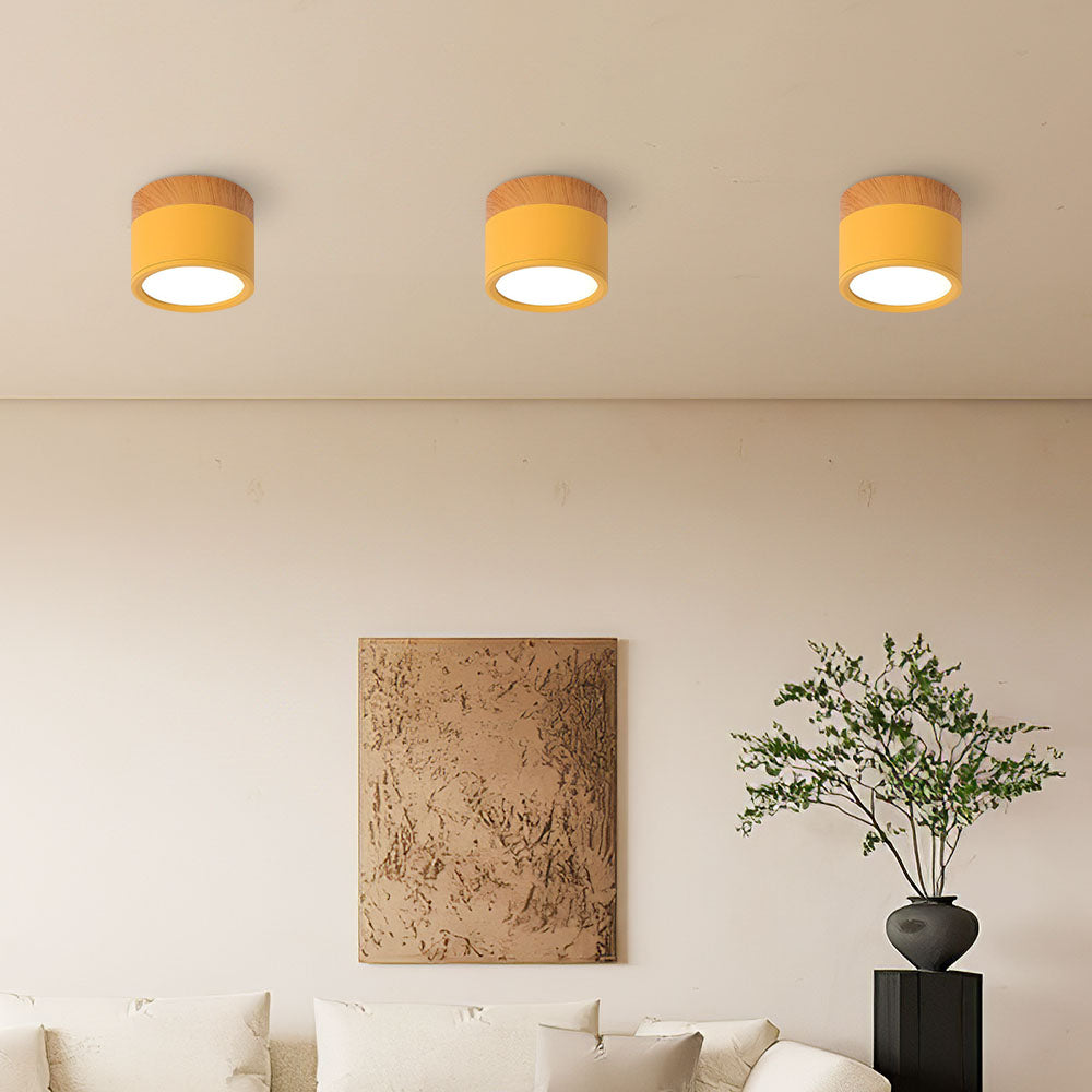 Three vibrant yellow cylinder surface spotlights illuminating a minimalist living room