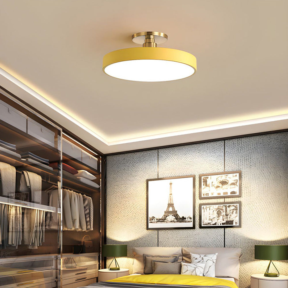 Vibrant yellow modern drum flush mount illuminating a warm, neutral bedroom