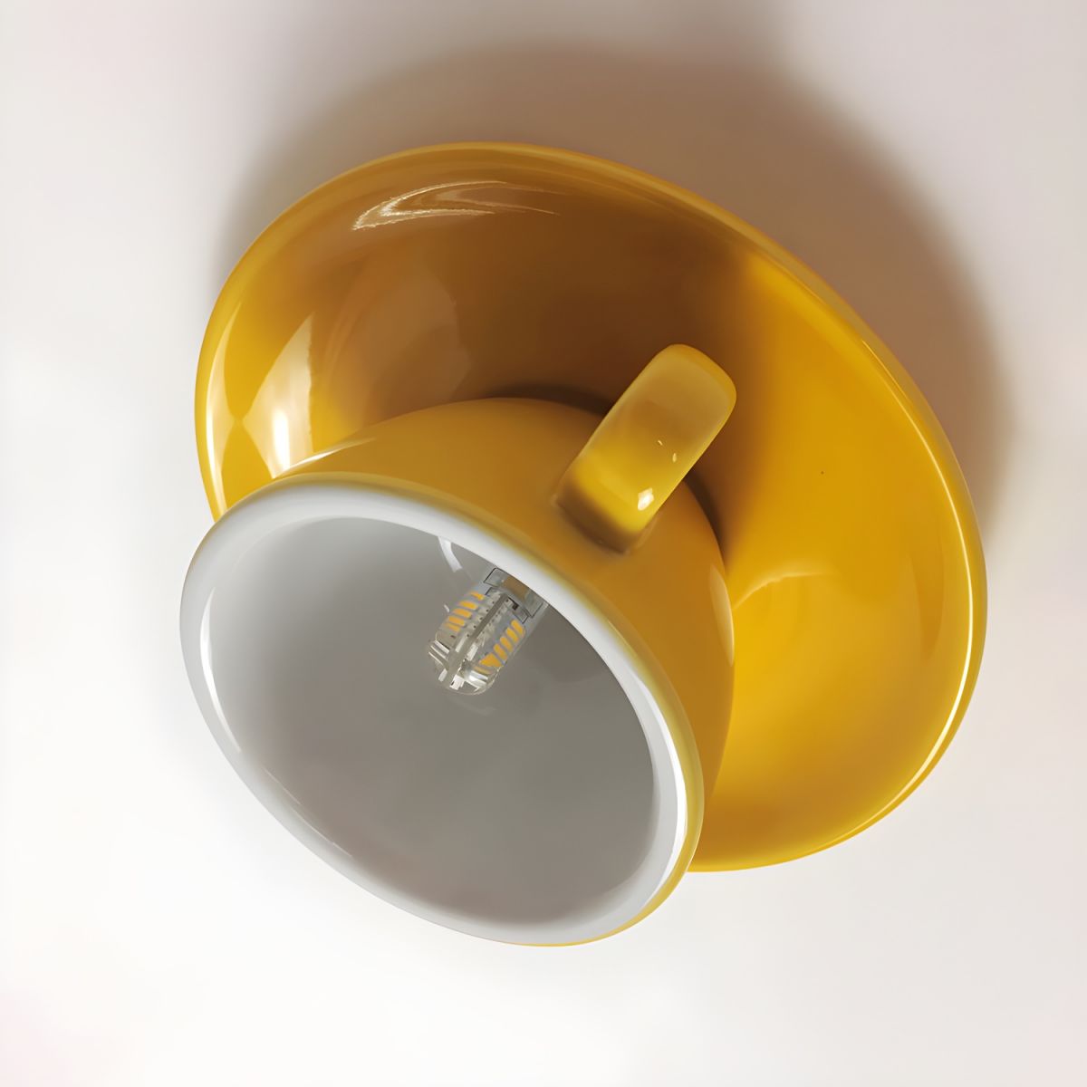 Angled close-up of the yellow teacup light interior showing the premium ceramic glaze and G4 LED bulb