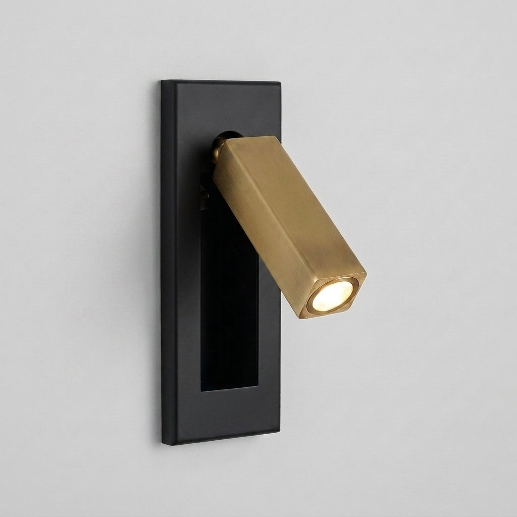 Zexto wall sconce in black and gold finish, illuminated, close-up view on a grey studio background