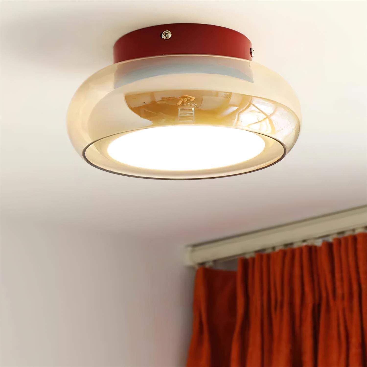Amber glass dome zuba ceiling lamp casting a warm ambient glow in a room with orange curtains