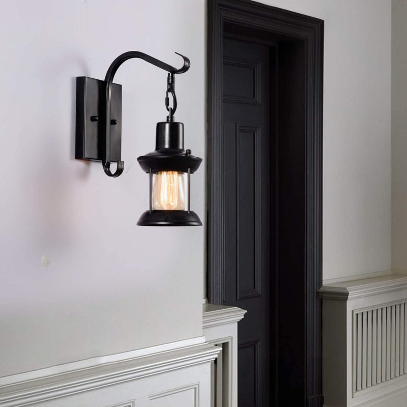 Black zupce hanging lantern wall sconce providing atmospheric lighting next to a dark hallway door