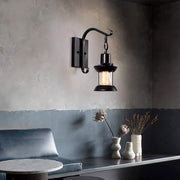 Black zupce vintage industrial lantern wall sconce illuminating a modern, moody living room space