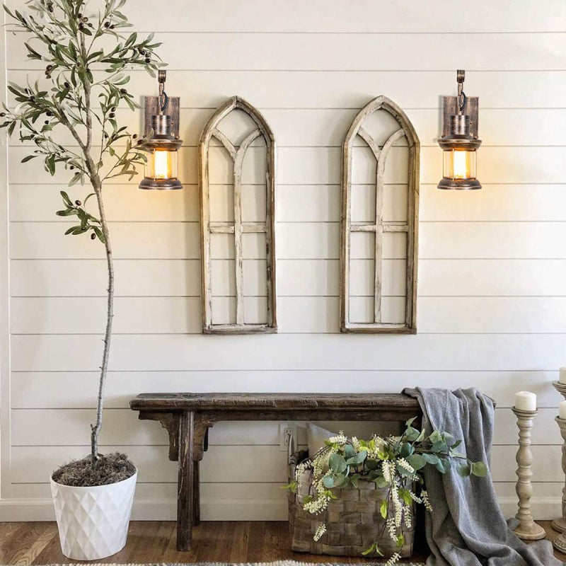 Pair of zupce rustic bronze wall sconces framing decorative arched window panes above a rustic hallway bench
