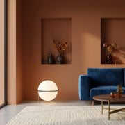 Zylpa Solo chrome sphere floor lamp beside a navy blue sofa in a terracotta living room